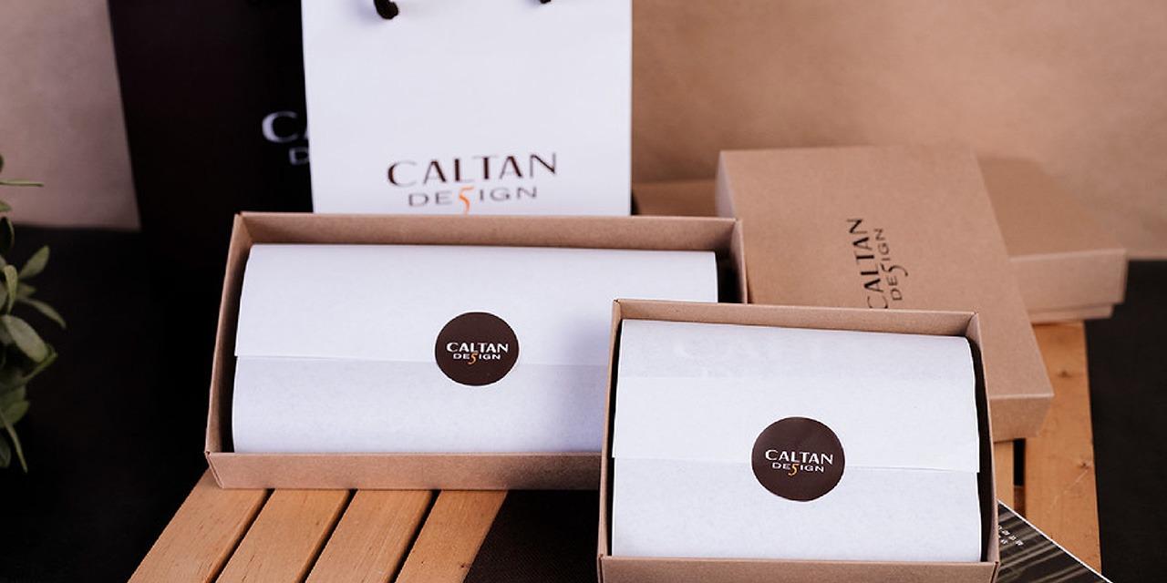 CALTAN DESIGN 桌上擺著兩個紙盒,紙盒裡有精美包裝