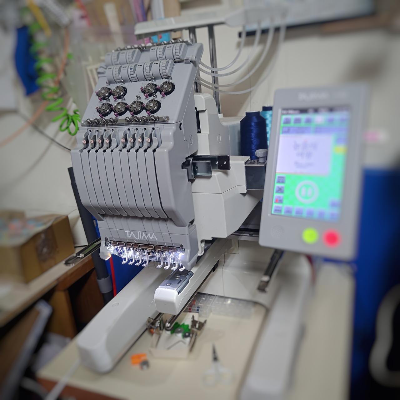 電腦刺繡工作室實拍，展示嫩嫩喵手作使用的 Tajima 電腦刺繡機與實際製作環境，從刺繡製版設定到機器繡製，呈現專注細節的刺繡創作流程。
